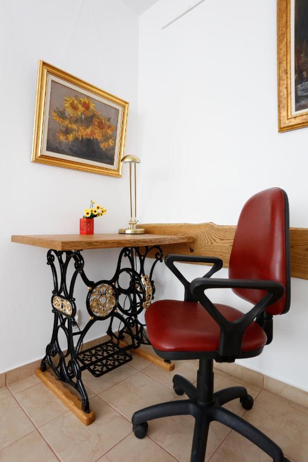 A desk on the cast-iron base of a sewing machine, with a red chair and a painting